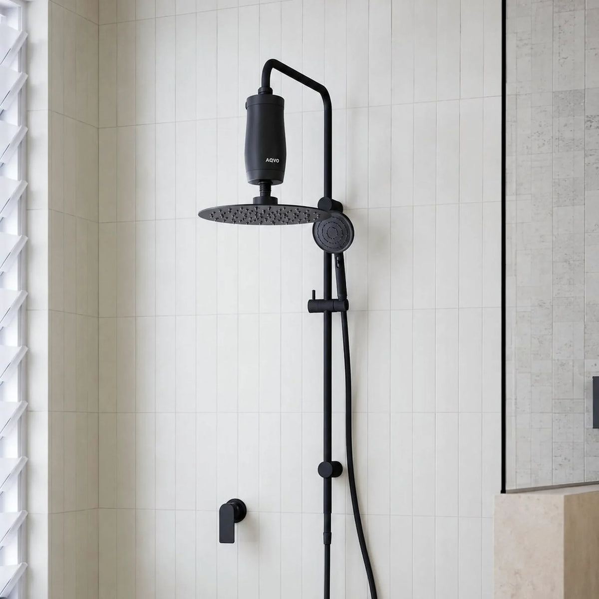 AQVO shower filter in matte black fitted above a black rainfall shower head on a matte-black rail shower