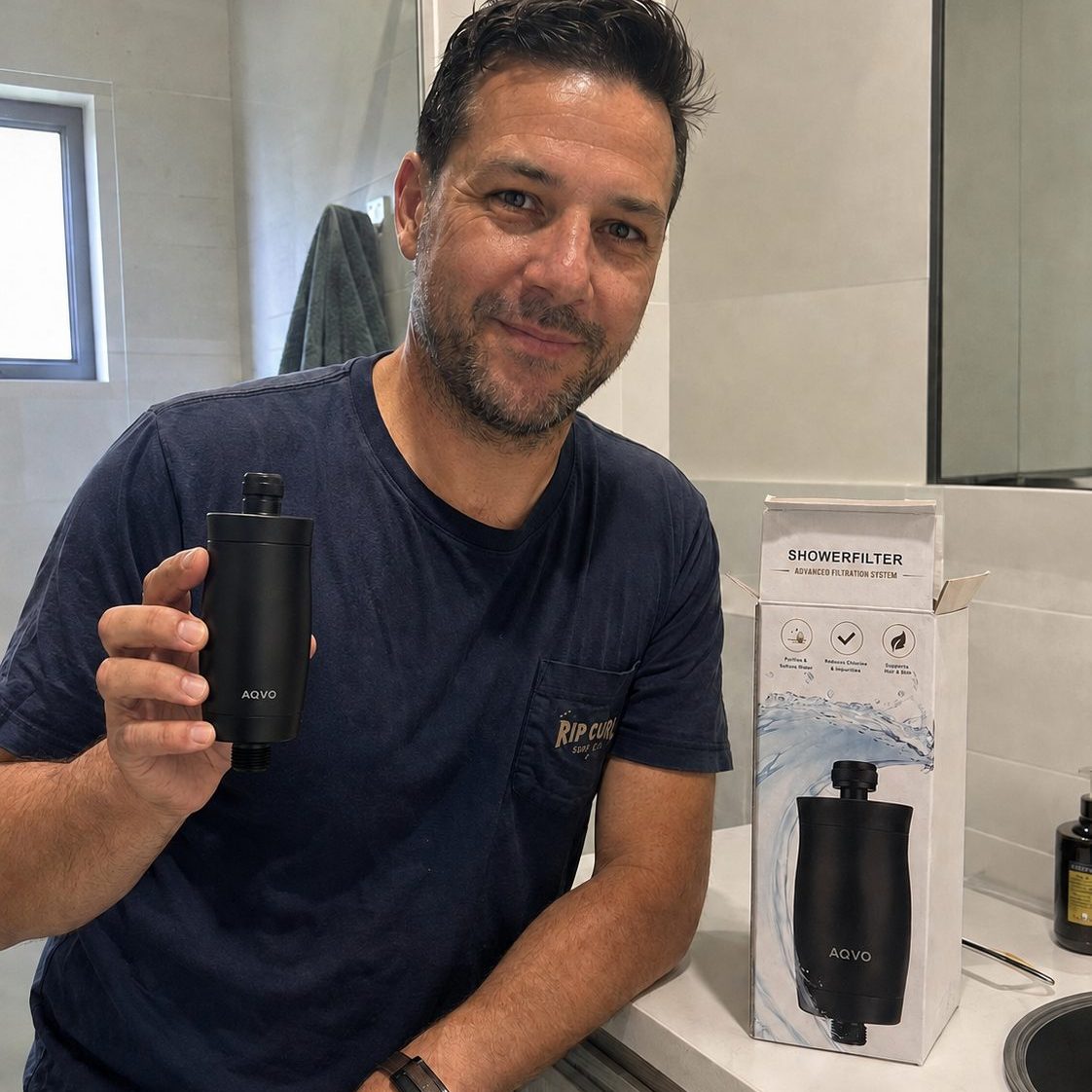 AQVO shower filter in matte black held next to its retail box in a bathroom