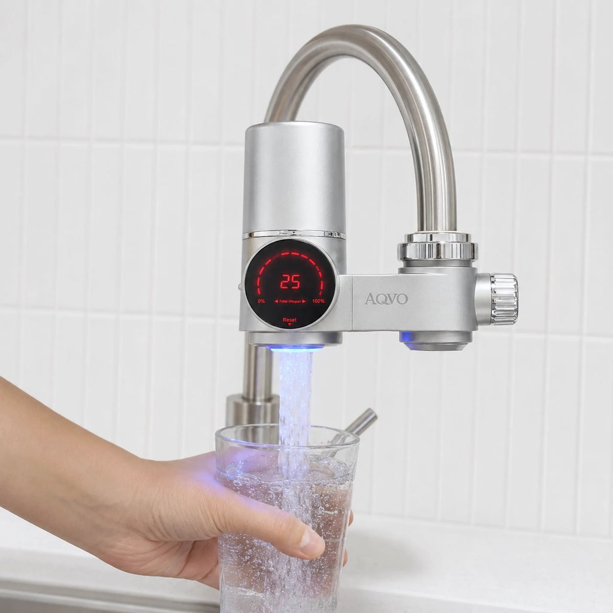 AQVO tap filter fitted to a kitchen mixer tap, filling a glass with the display lit while water flows